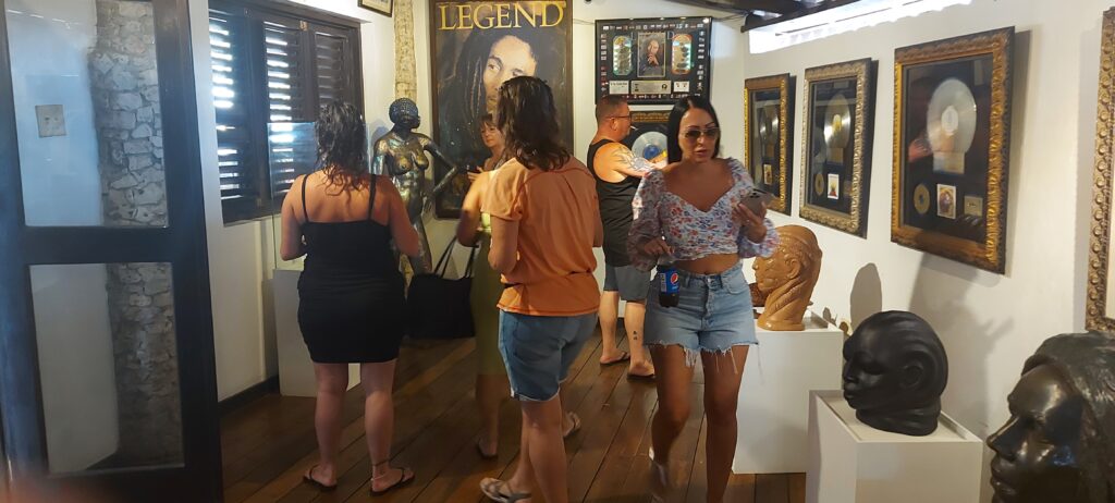 Visitors walk through a small room at Nine Mile filled with Bob Marley memorabilia, looking and taking pictures.