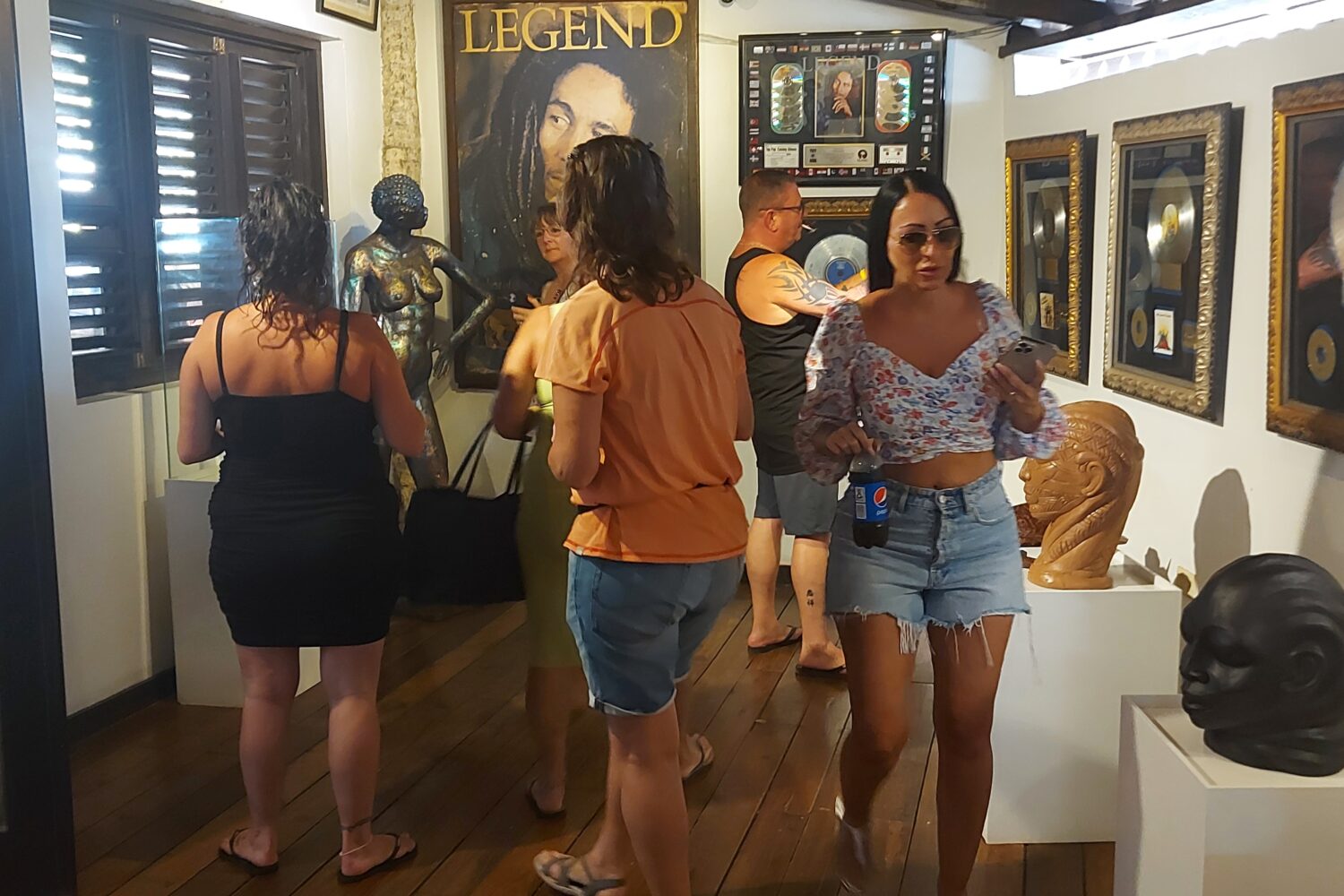 Visitors walk through a small room at Nine Mile filled with Bob Marley memorabilia, looking and taking pictures.