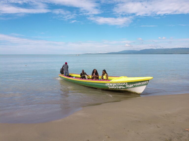 Three visitors sit in a local fishing boat with the captain seated behind them, preparing to take the group across the water to the Pelican Bar