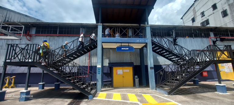 "Visitors climbing the stairs to enter the Appleton Estate distillation factory during a private rum tour in Jamaica.