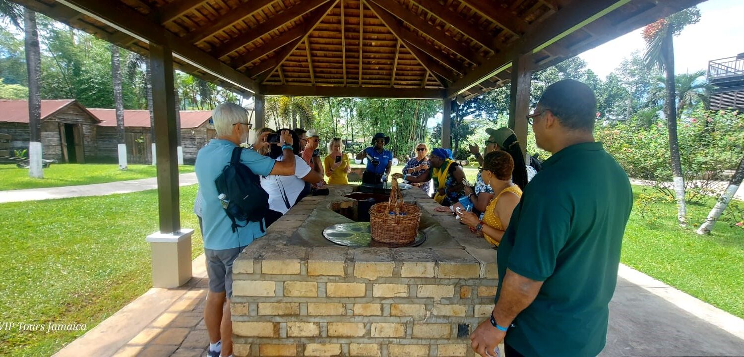 Visitors gathered around inside the molasses station at Appleton Estate, listening to a tour guide explain the history of molasses making while receiving samples to taste.