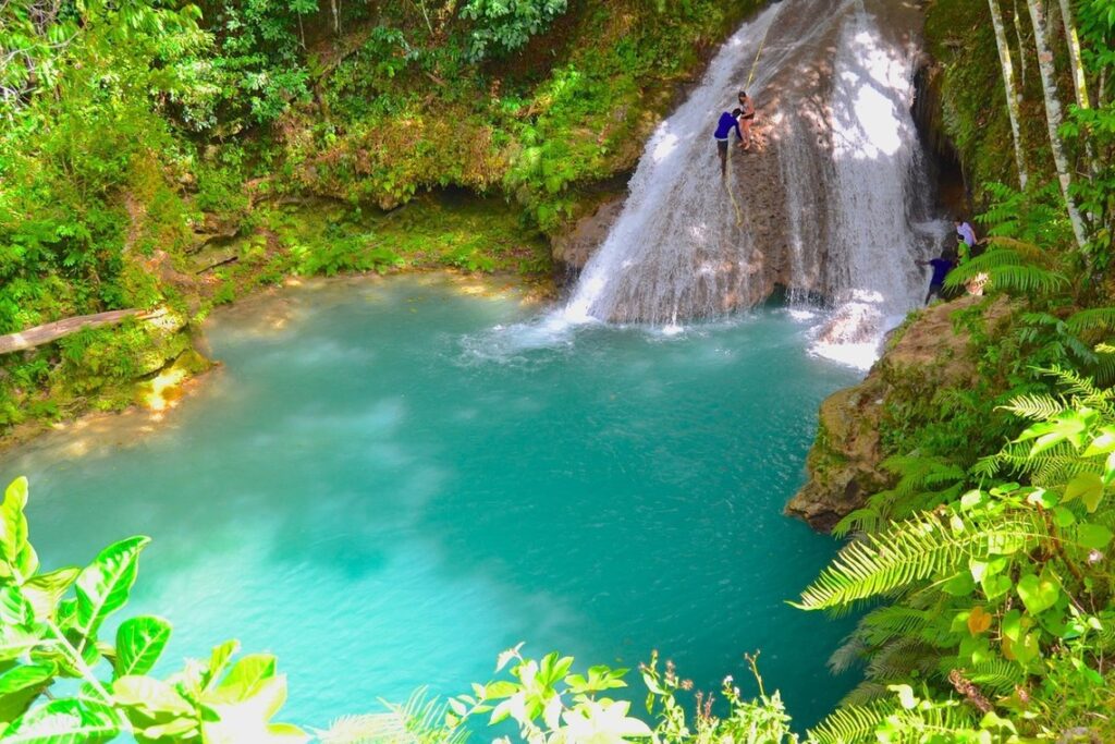 Guide climbing Blue Hole falls as visitors enter cave