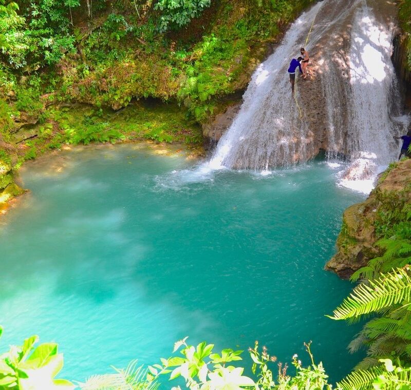 Guide climbing Blue Hole falls as visitors enter cave