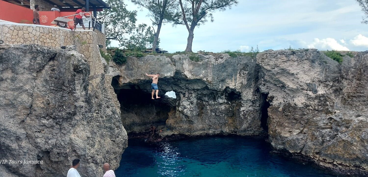 A man leaps from the cliff at Rick’s Café in Negril, Jamaica, plunging into the Caribbean waters below as spectators watch the thrilling moment.