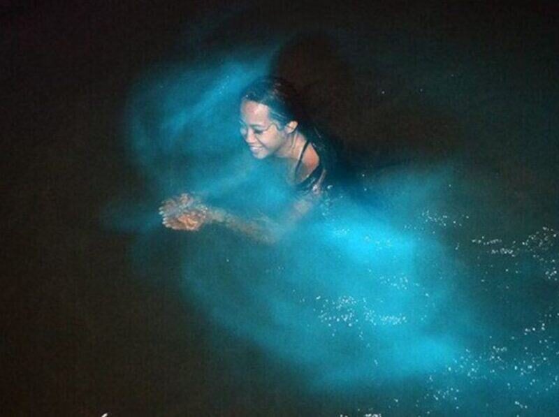 Woman swimming in Jamaica’s Luminous Lagoon at night, surrounded by glowing bioluminescent waters near Falmouth, Trelawny.