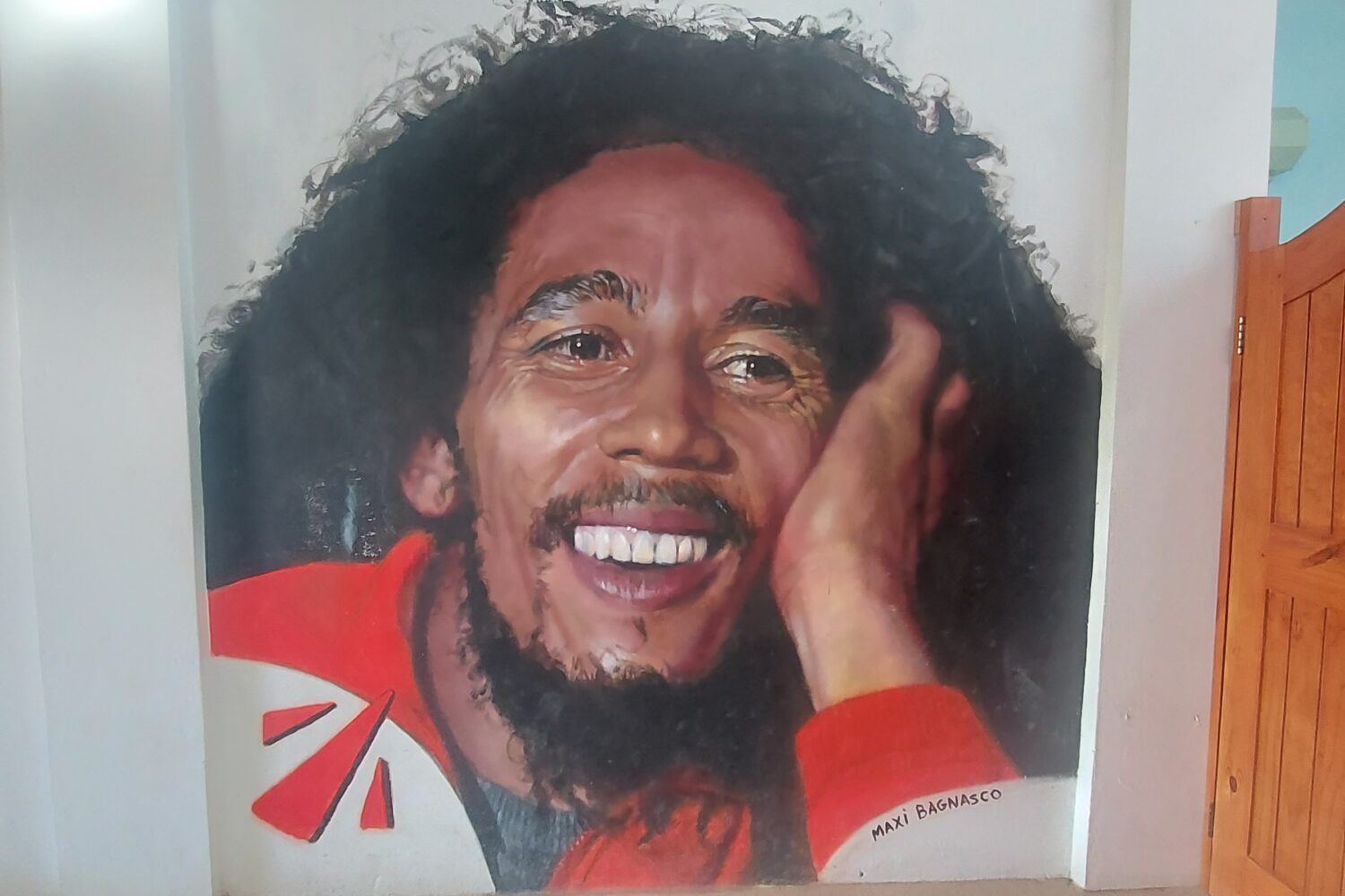Colorful mural of Bob Marley painted on a wall at the Nine Mile attraction in Jamaica, showing him with his iconic dreadlocks and warm expression