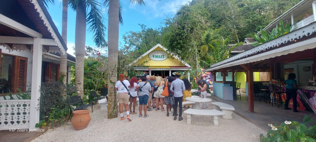 A group of visitors walk toward a building marked with a Nine Mile sign at the Bob Marley attraction in Jamaica.