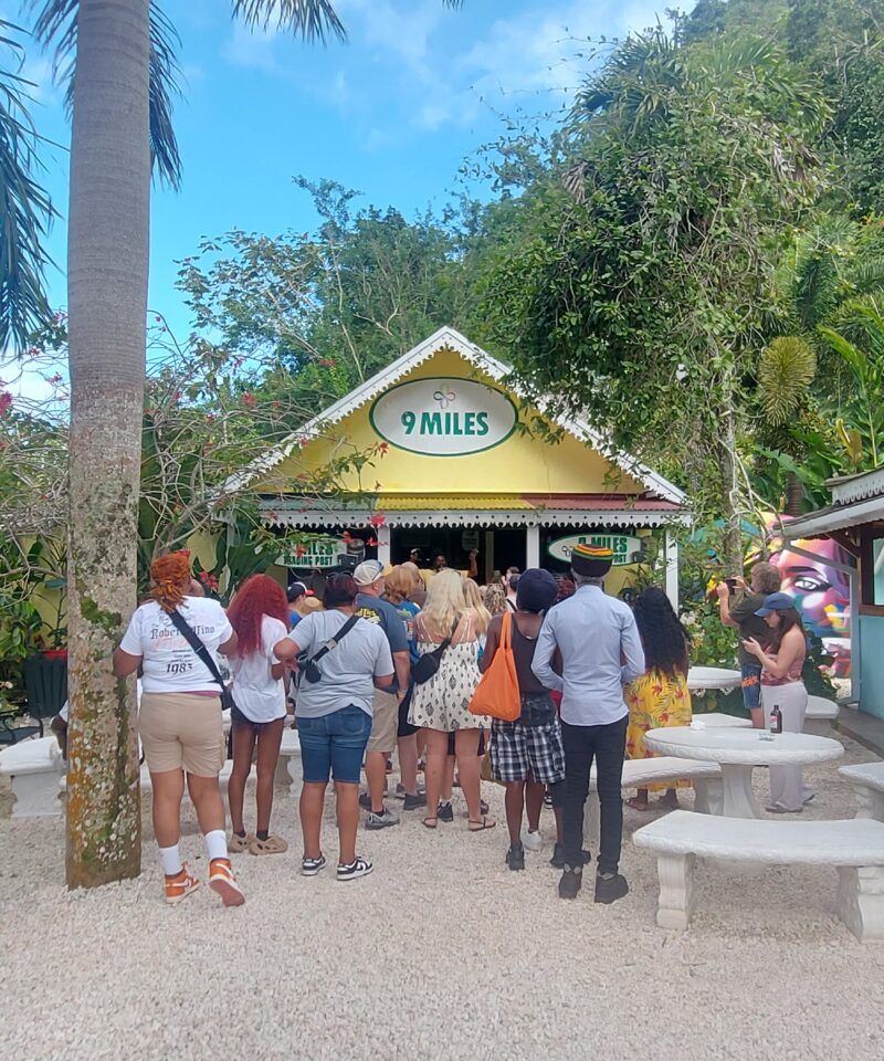 A group of visitors walk toward a building marked with a Nine Mile sign at the Bob Marley attraction in Jamaica.