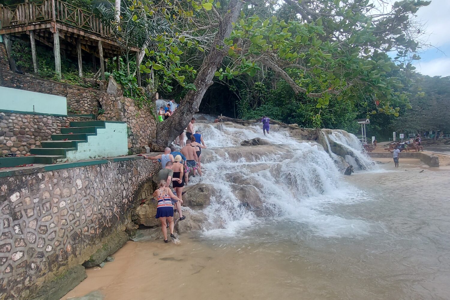 Water flowing over huge rocks into the sea. People in a line climbing the rock