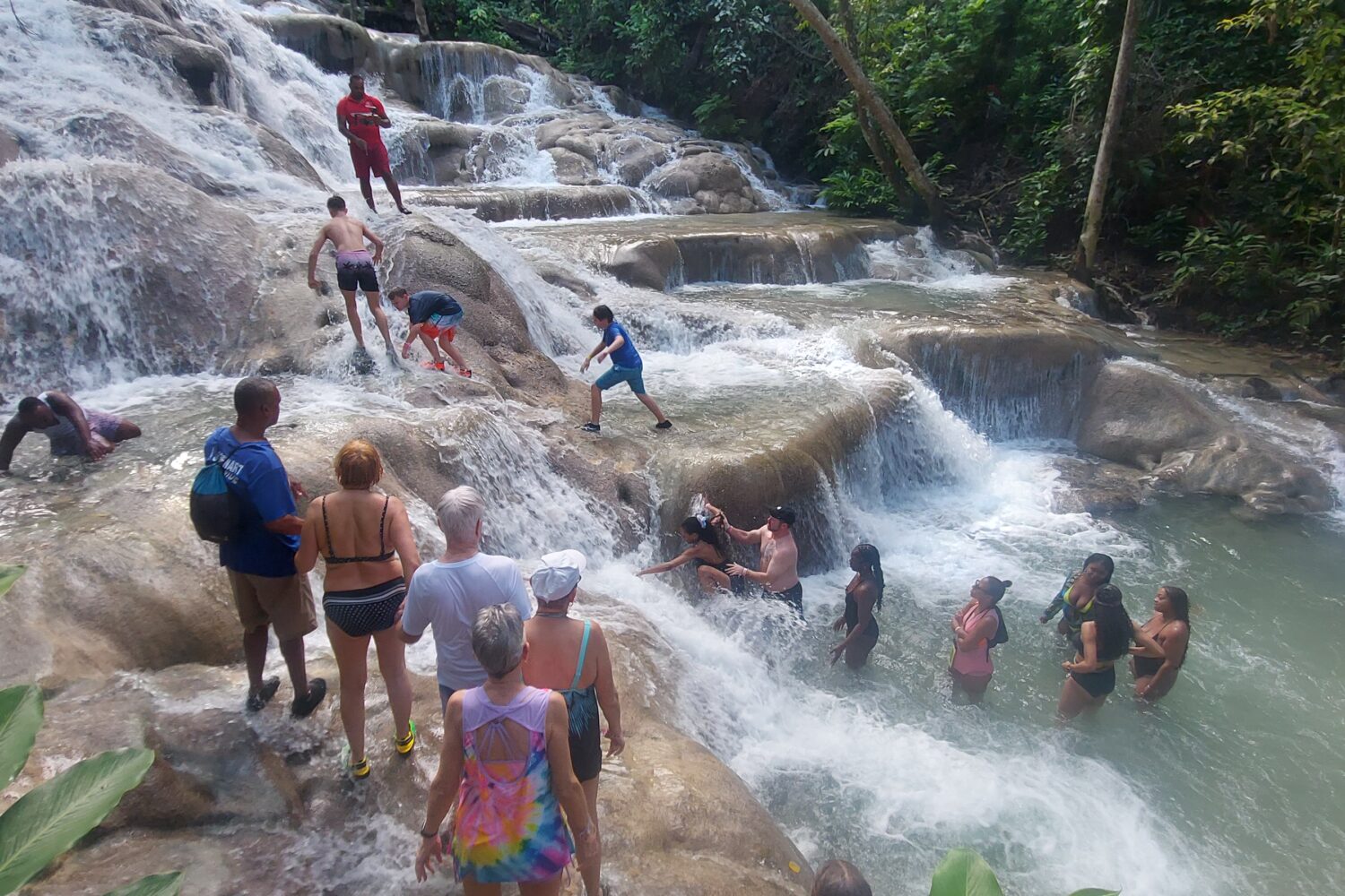 People standing on huge rocks with water flowing over it