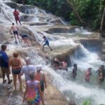 People standing on huge rocks with water flowing over it