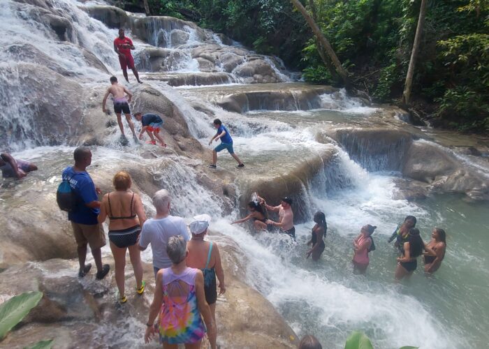 People standing on huge rocks with water flowing over it