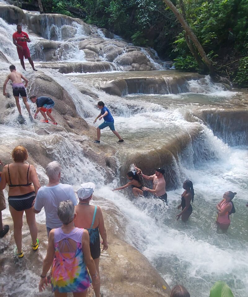 People standing on huge rocks with water flowing over it