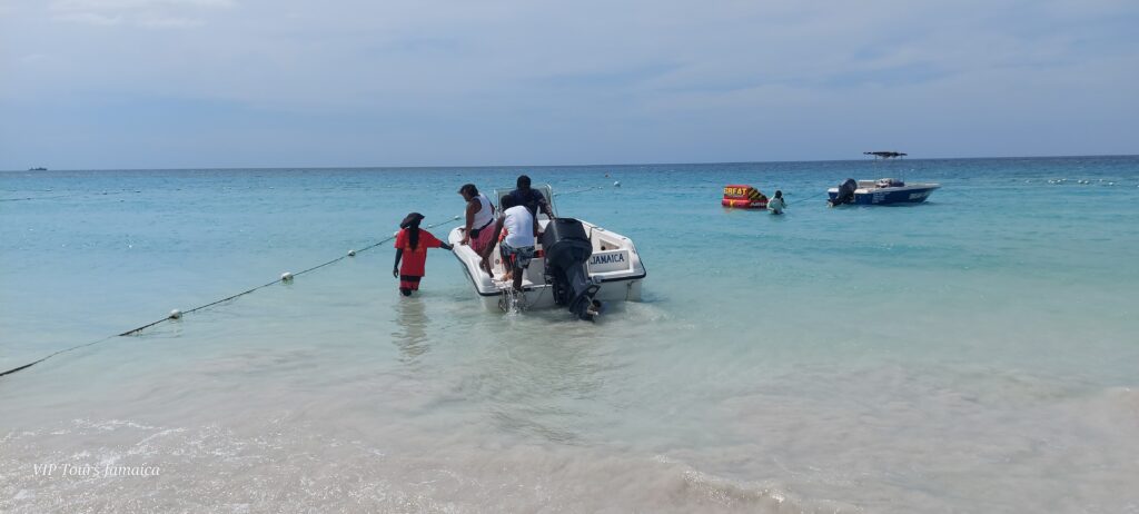 A white boat in the sea with people climbing on board