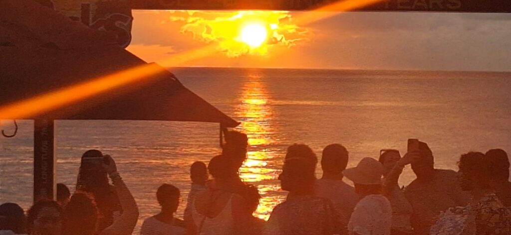 People standing together. A bright sun orange sun in the sky over the sea