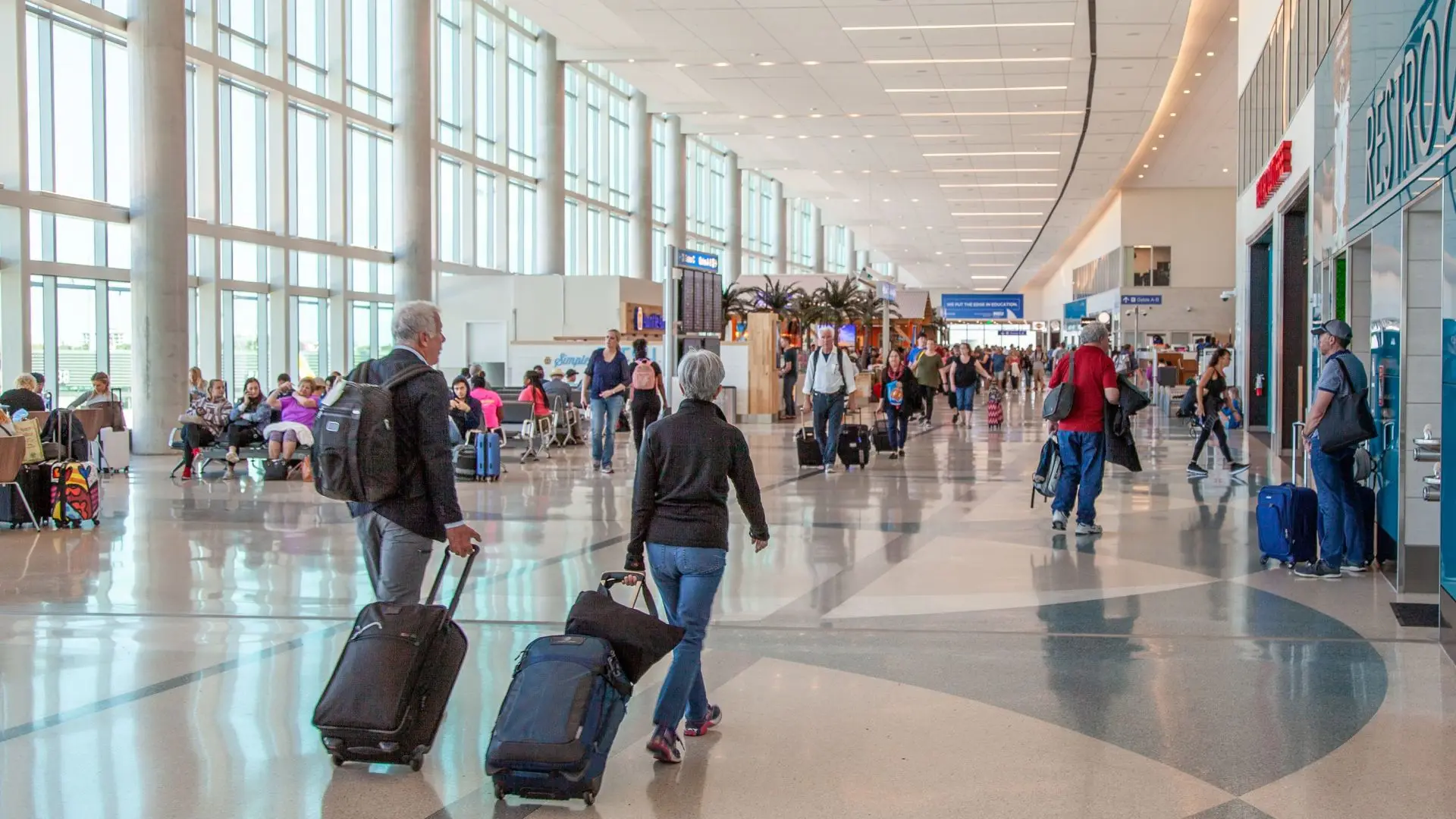 Interior of a busy airport terminal with travelers moving through the concourse